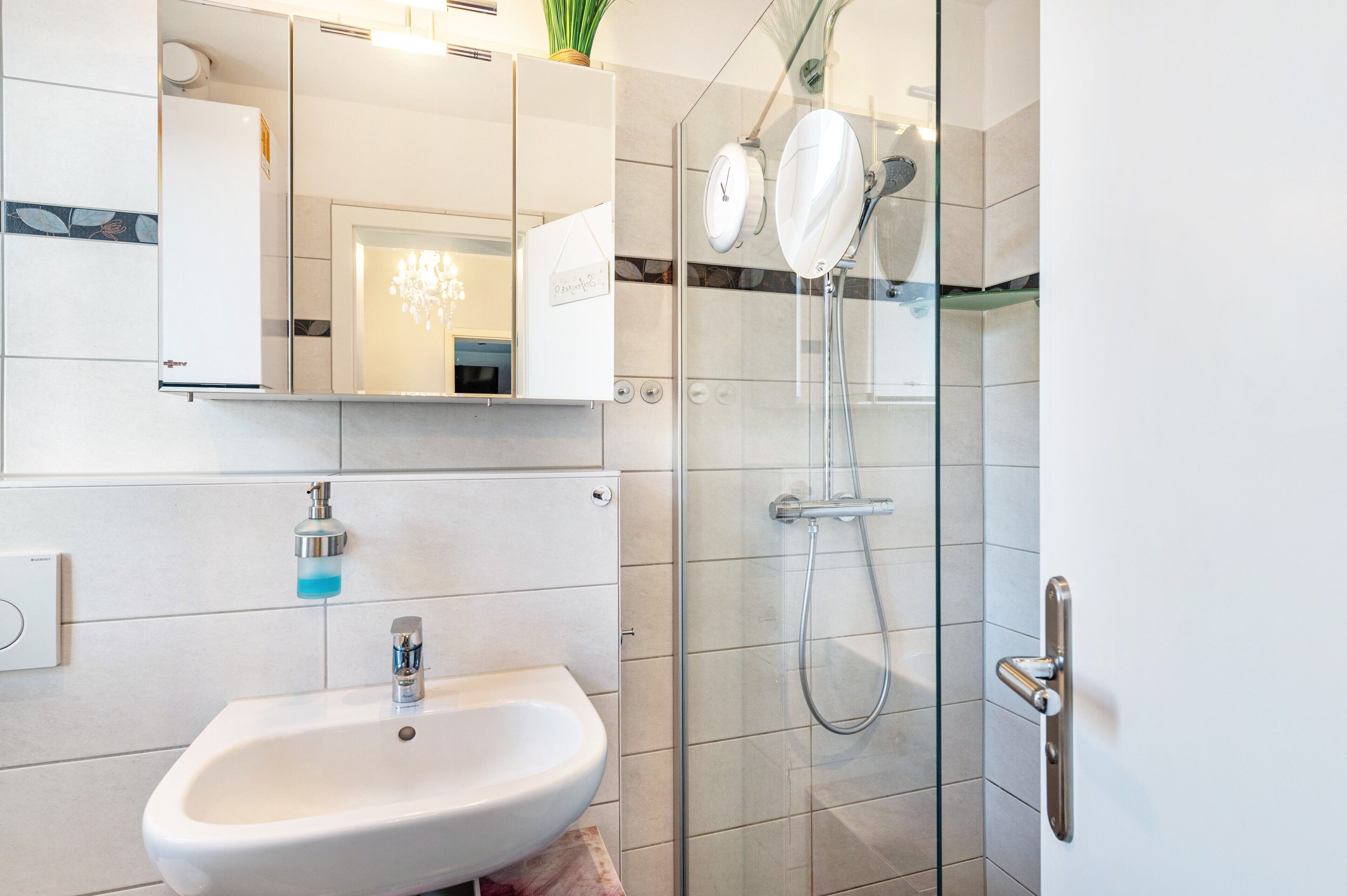 A modern bathroom with a glass-enclosed shower, a white sink, and a mirror above the sink.