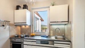 A modern kitchen with a built-in oven, dishwasher, and stainless steel sink.