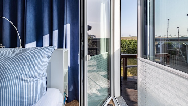 A room with a bed, a window with curtains, and a view of the outdoors.