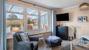 A modern living room with a sofa, ottoman, and a TV mounted on the wall.