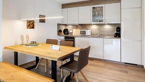 Eine moderne Küche mit weißen Schränken, einem Holzespeisetisch und einer Bank.