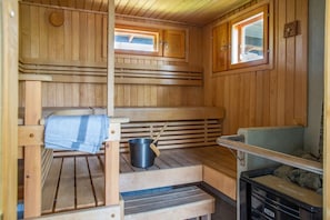 Eine Sauna mit Holzbänken, einem Eimer und einem Ablagebereich für Steine.
