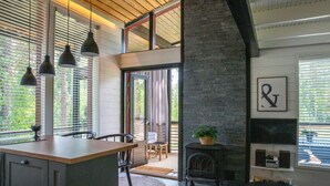 A modern kitchen with a wooden island, pendant lights, and a stone fireplace.