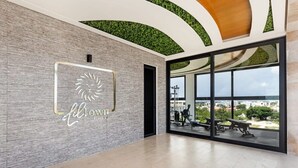A modern interior with a logo on the wall, a large glass door leading outside, and a view of the cityscape. - Chic Studio by 5th Ave with Rooftop Pool and Gym (Playa del Carmen)