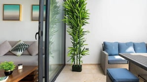 A modern living room with a sofa, a dining table, and a tall green plant. - Chic Studio by 5th Ave with Rooftop Pool and Gym (Playa del Carmen)