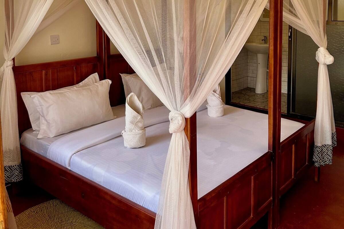 A four-poster canopy bed with a wooden frame and white bedding.