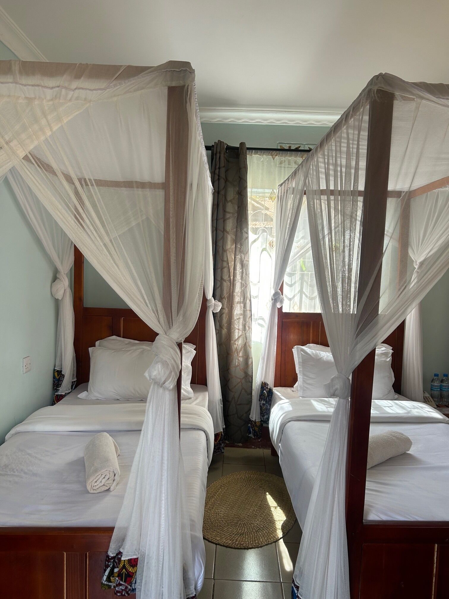 A room with two beds, each with a canopy bedspread and pillows.