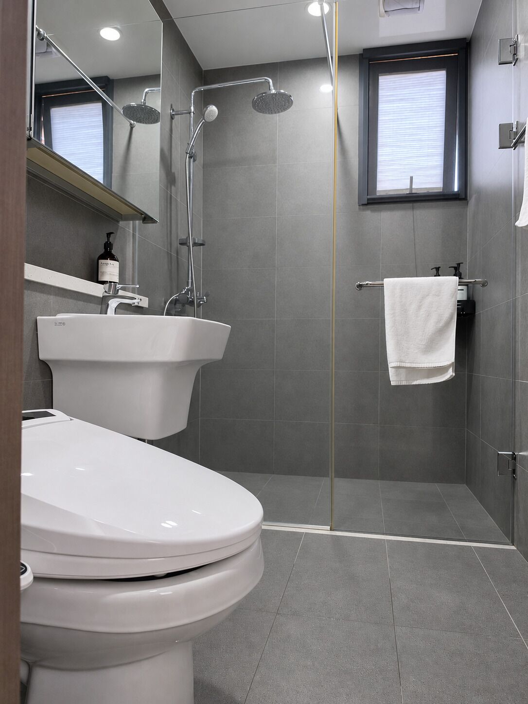 Un baño moderno con inodoro, lavamanos y ducha.