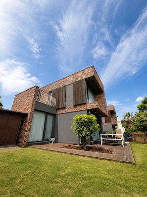 A modern two-story house with a brick facade, large windows, and a small garden. - Somsom House (Seogwipo)