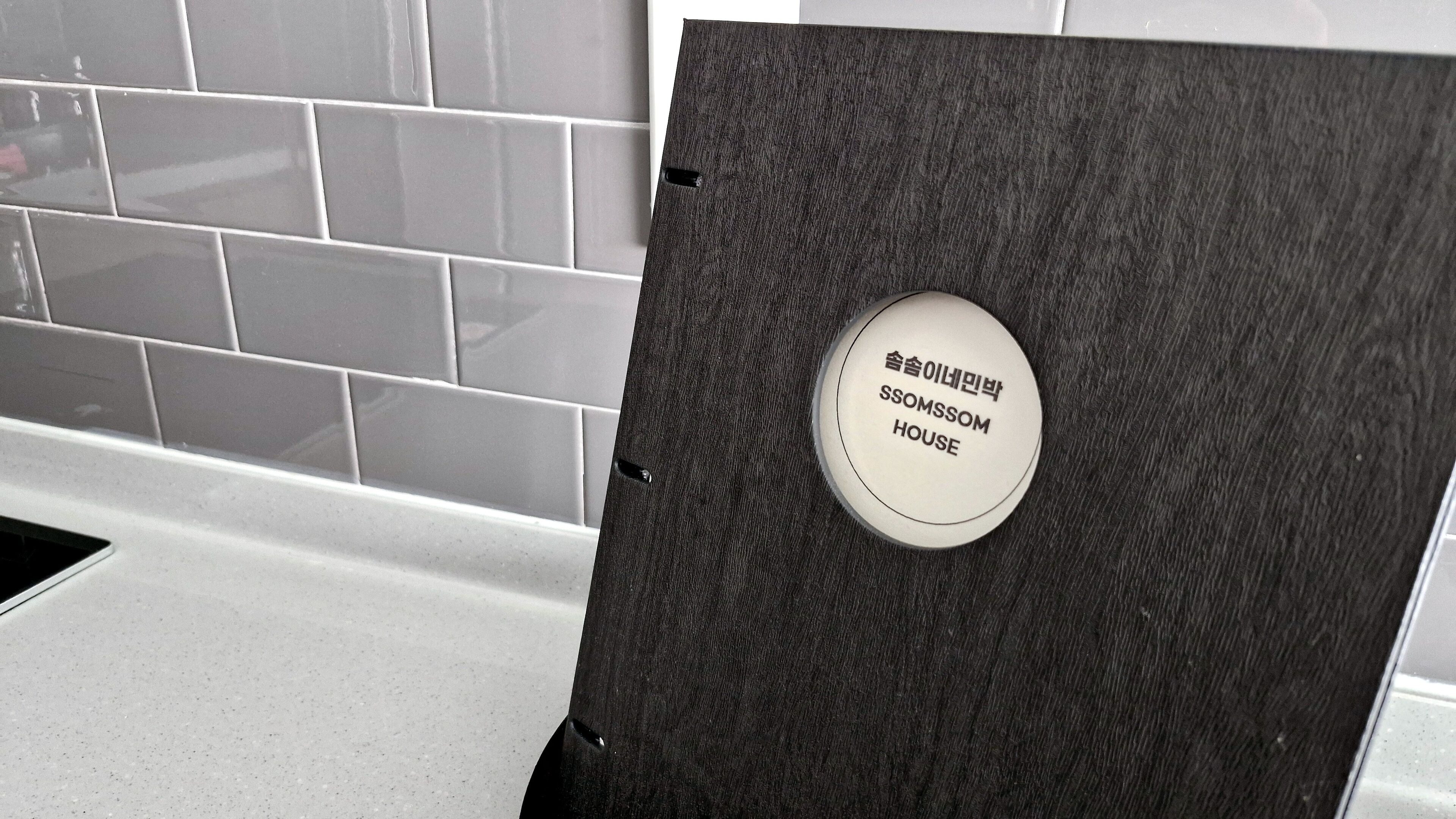 A bathroom with a dark textured door and a white tiled wall.