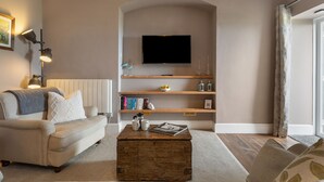 A living room with a sofa, coffee table, and TV mounted on a wall. - Caldey Island View - Sea Views and Log Burner (Tenby)