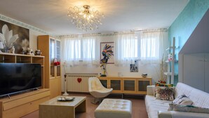 A modern living room with a flat-screen TV, a white sofa, a coffee table, and a decorative chair. - Awesome home in Castel Colonna di Mont (Castel Colonna di Mont)