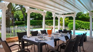An outdoor dining area with a covered pergola, white columns, and wicker chairs. - Awesome home in Castel Colonna di Mont (Castel Colonna di Mont)