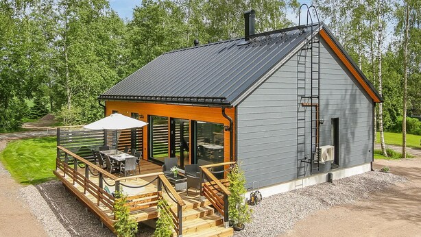A modern cabin with a deck, outdoor seating, and a large window. - Lukupirtti by Interhome (Säkylä)