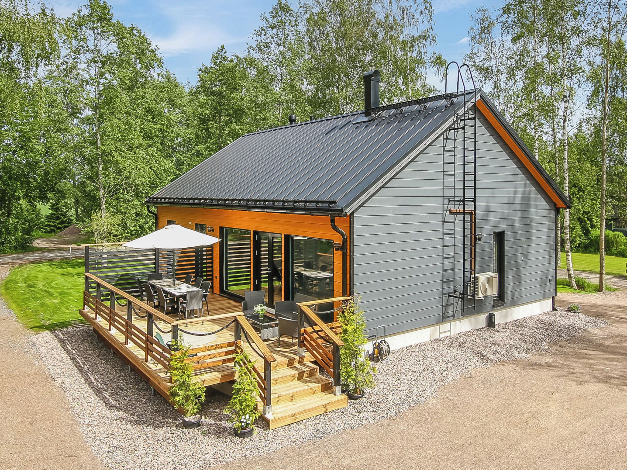 Pieni, yhden kerroksen rakennus, jossa on katettu terassi ja ulkona oleva oleskelualue.