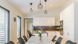 A modern kitchen with white cabinets, a black backsplash, and a marble-patterned dining table with black chairs. - Lukupirtti by Interhome (Säkylä)