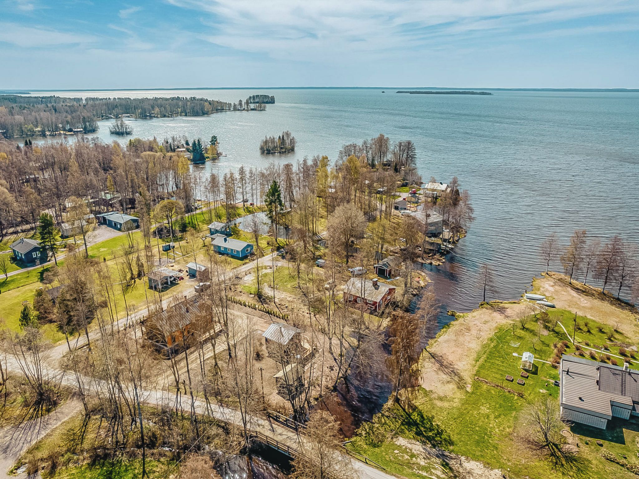 An aerial view of a lakeside property with multiple houses, a dock, and a clear view of the lake.
