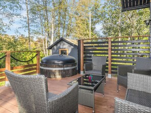 An outdoor deck with wicker furniture, a hot tub, and a wooden structure. - Lukupirtti by Interhome (Säkylä)