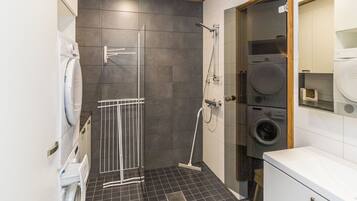 Ein modernes Badezimmer mit Dusche, Waschmaschine und Trockner.