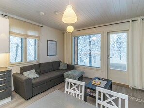 A cozy living room with a sofa, a small table, and a window with a view of trees.