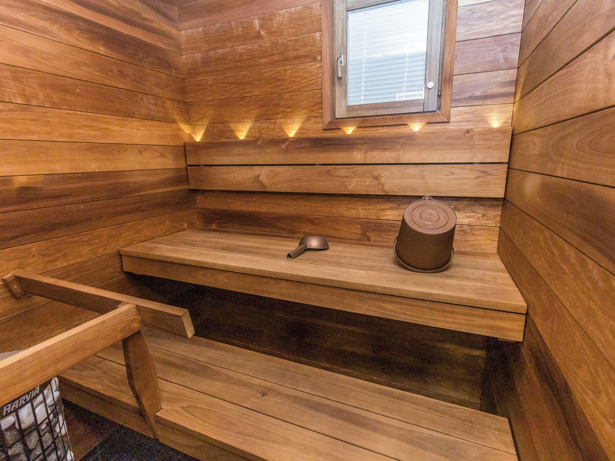 Een houten sauna met een bank, een handdoek en een emmer.