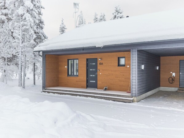 A wooden cabin with a black door labeled '10A' in a snowy landscape.