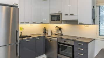 A modern kitchen with stainless steel appliances, white cabinetry, and a built-in oven.