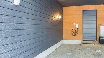 L’extérieur d’un bâtiment avec un mur en bois gris, une porte en bois et un sol en béton.