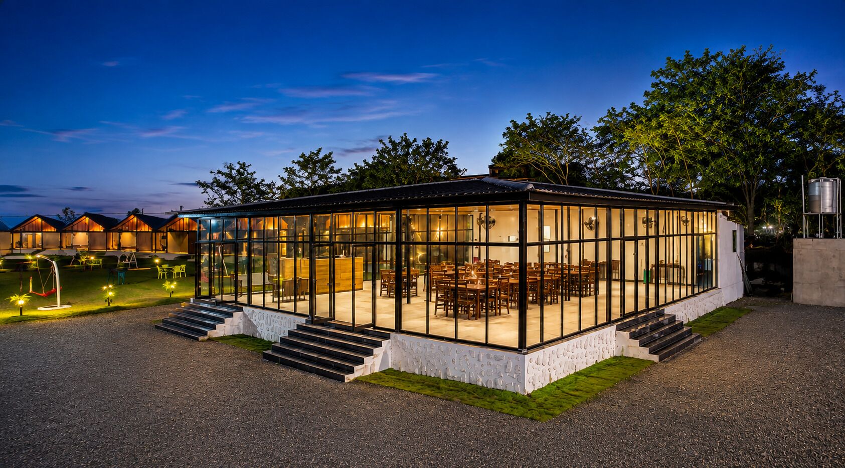 Un edificio moderno de vidrio con un comedor y escalones que llevan a la entrada.