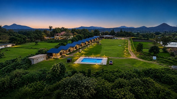 A resort with multiple guest buildings, a swimming pool, and a mountainous backdrop. - Shreephal Luxurious Resort (Hatgad, Nashik)