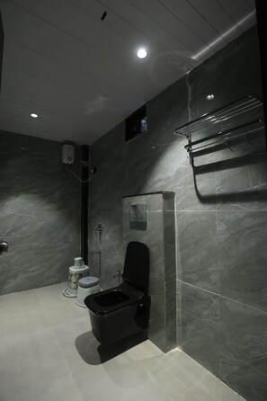 Un baño moderno con inodoro negro, paredes de mármol y zona de ducha.