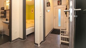 A hallway with a bed, a sink, and a door leading to another room. - Townhouse Thaden - mid-terrace house in Norddeich for up to 4 people (Norden)