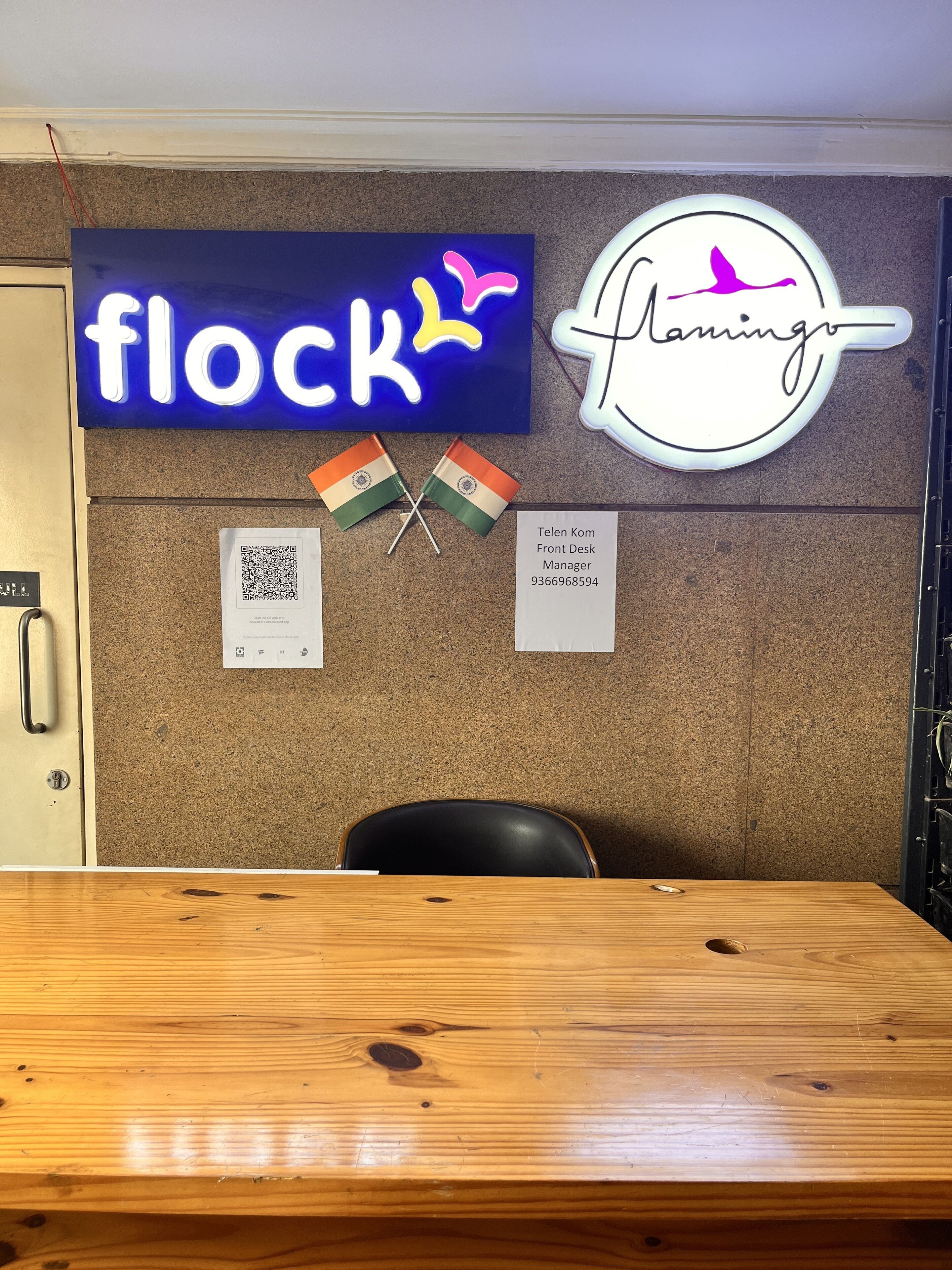 Een receptiebalie met een bordje 'flock', een 'Planning' bordje, twee Indiase vlaggen en een bordje 'Telen Kom Front Desk Manager'.