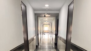 A long, narrow hallway with a shiny, reflective floor and dark trim. - Hotel Flamingo (Gurugram)