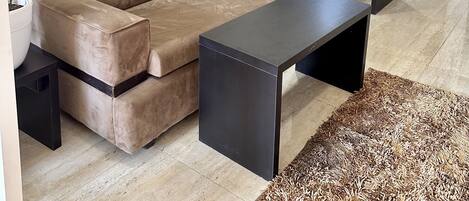 A modern living room with a beige sofa, a black coffee table, and a potted plant.