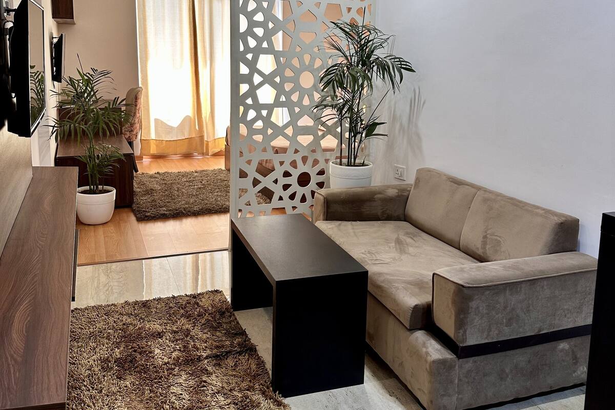 A modern living room with a sofa, coffee table, and decorative plants.