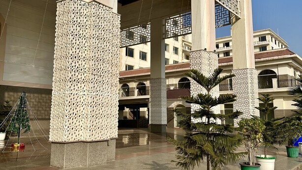 A building with a covered entrance, columns with intricate patterns, and potted plants. - Hotel Flamingo (Gurugram)