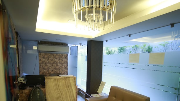 A modern interior with a beige sofa, a wooden cabinet, and a glass wall with notes. - Hotel Comfotel (Kolkata)