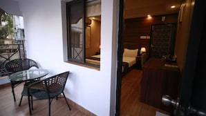 A hotel room with a bed, a small table, two chairs, a window, and a door. - Hotel Comfotel (Kolkata)
