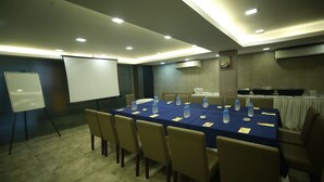 A conference room with a long table, chairs, a whiteboard, and a projector screen. - Hotel Comfotel (Kolkata)
