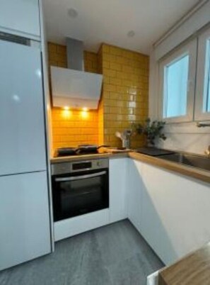 Une cuisine de taille réduite, avec des meubles blancs, une cuisinière et un évier.