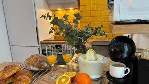 Ein Frühstückstisch mit Croissants, Orangensaft, einem Entsafter und einer Kaffeemaschine.