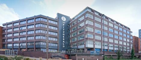 En moderne bygning med flere etager, store vinduer og et tydeligt skilt med teksten 'The Fitzgerald'.