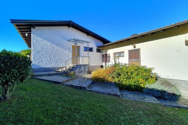 Ein modernes Haus mit einem gepflasterten Weg, der zum Eingang führt, umgeben von gepflegter Bepflanzung.