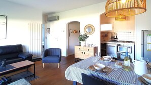 Un salon moderne avec un canapé, une table à manger pour deux personnes et un coin cuisine équipé d’un four à micro-ondes et d’une cuisinière.