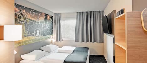 A hotel room with a bed, a desk, a TV, and a painting on the wall.