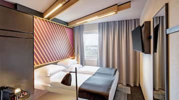 Een moderne hotelkamer met een bed, nachtkastje en een aan de muur bevestigde televisie.