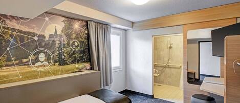 A hotel room with a bed, a shower area, and a large window with a view of a landscape.