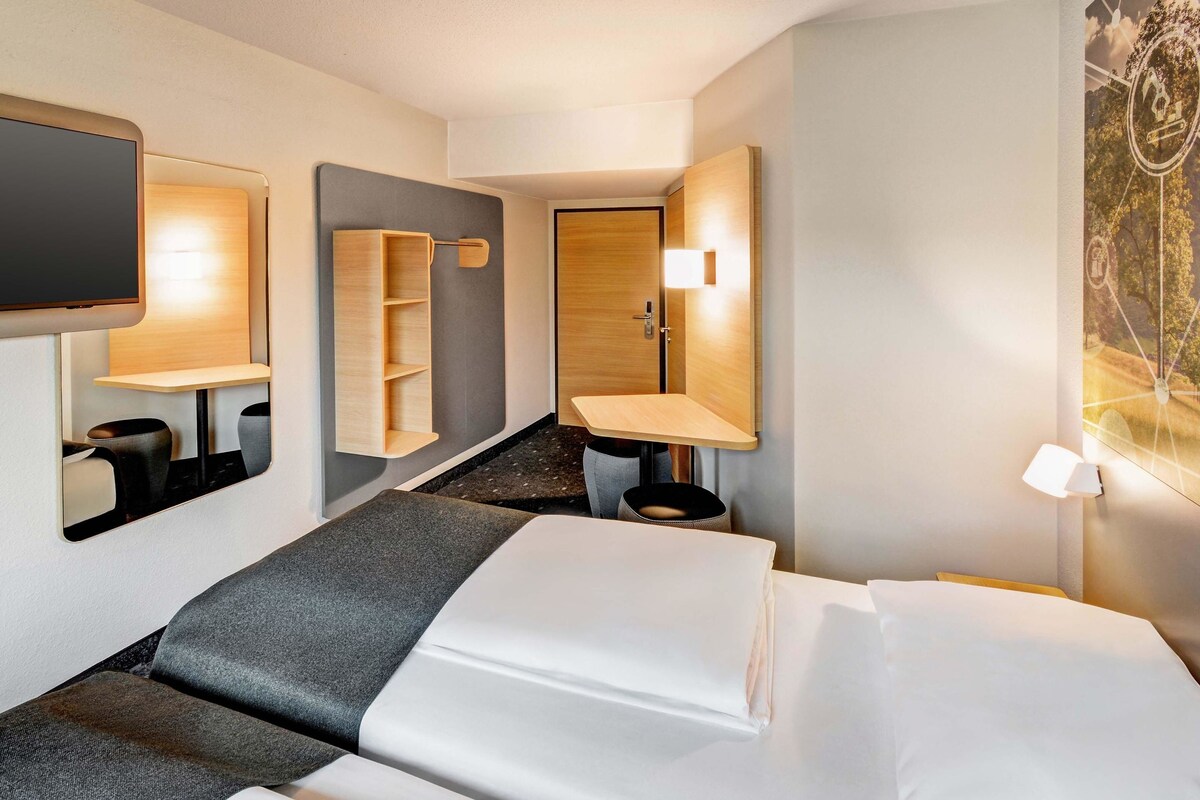Une chambre d’hôtel avec un lit, une télévision, un bureau et une salle de bain.