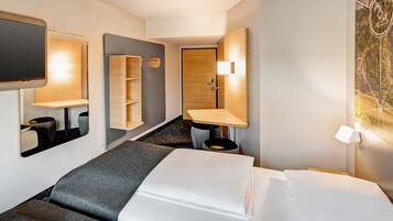 Habitación de hotel con cama, televisor, escritorio y baño.